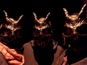 Three theatre goers dressed in dark cloaks and wearing black Donnie Darko masks